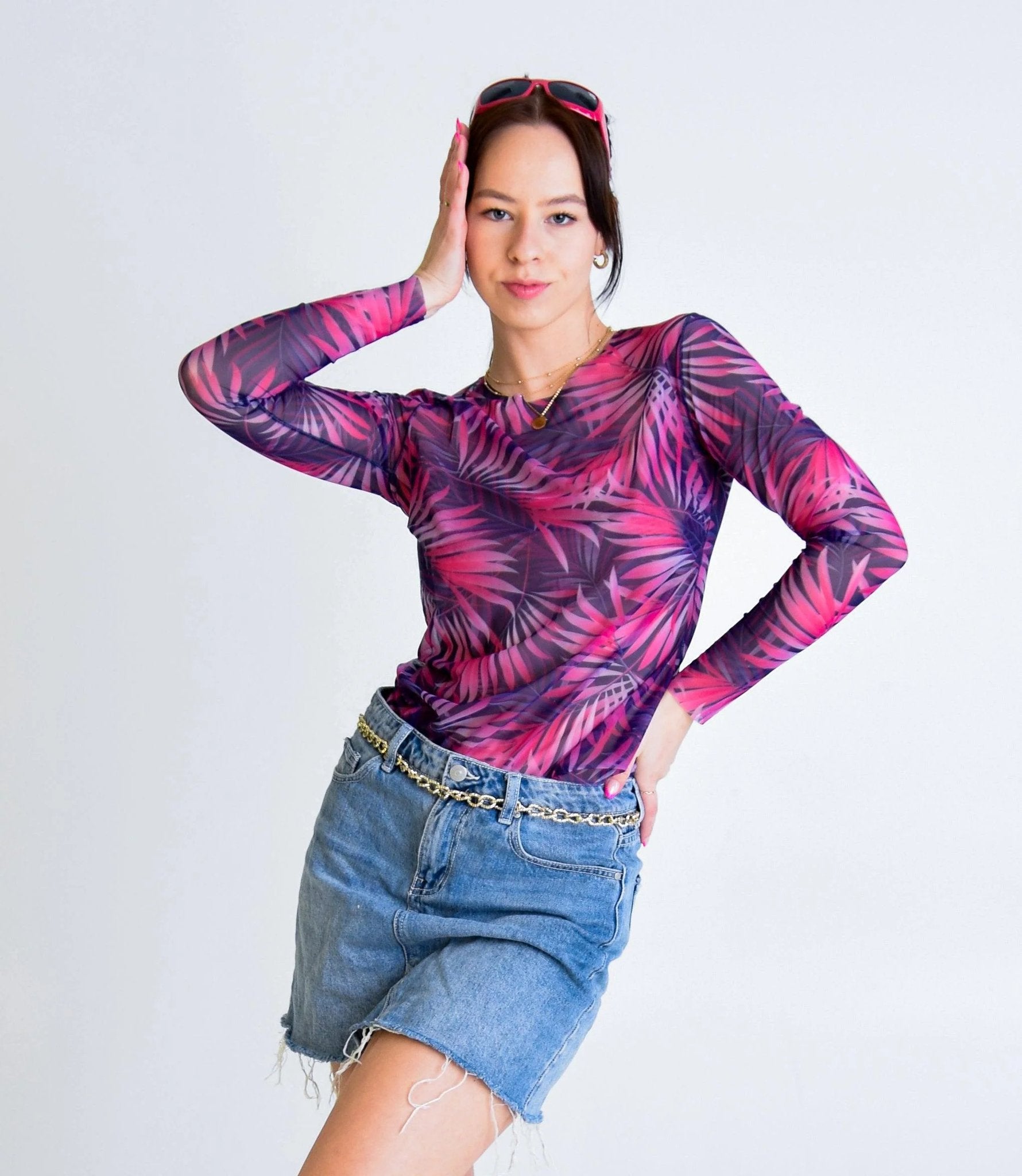 1. Women's tan-through long-sleeve shirt in pink Tropica pattern, worn by model with denim skirt in studio setting