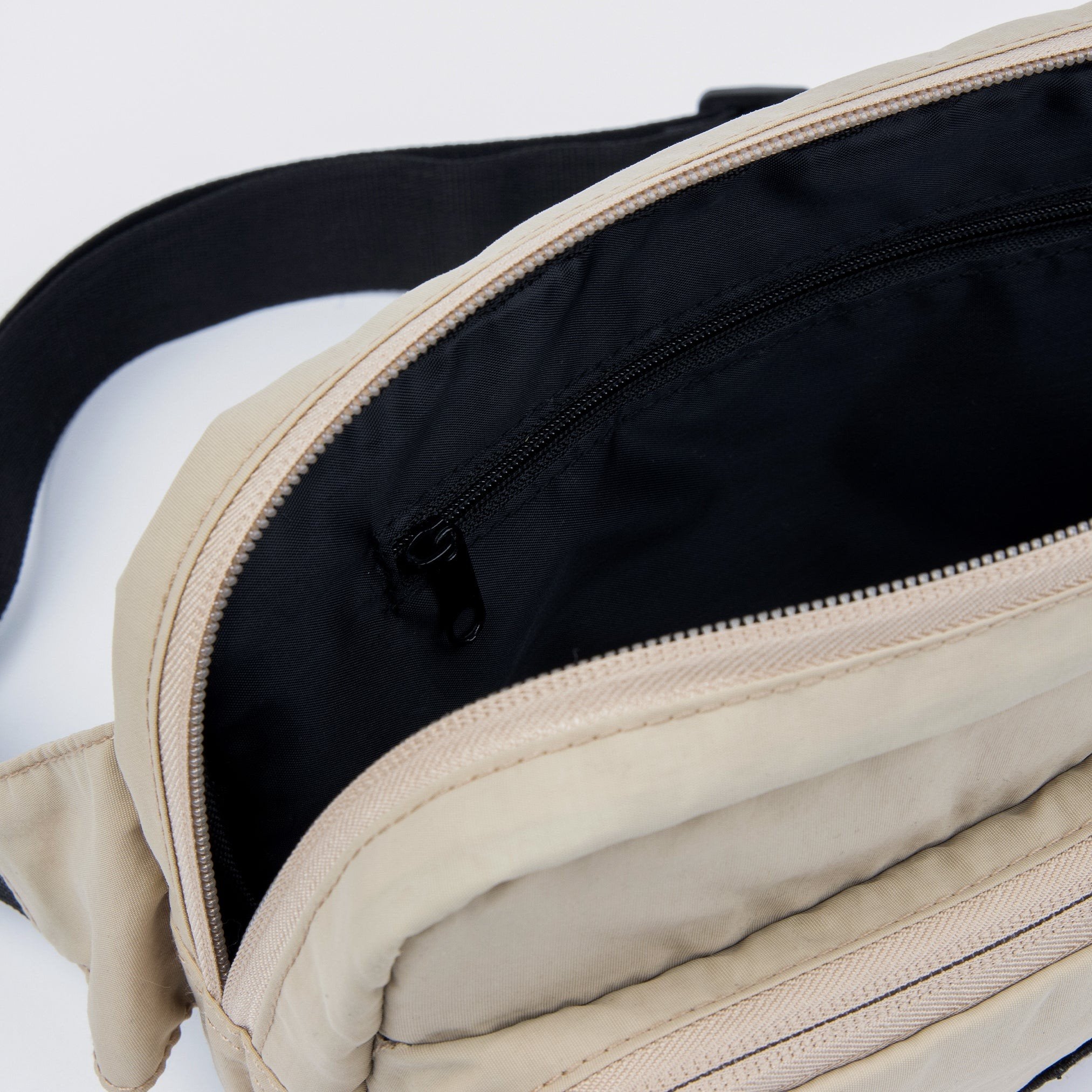 3. Interior view of beige Sniff Retro Waist Bag with black lining and zipper pocket