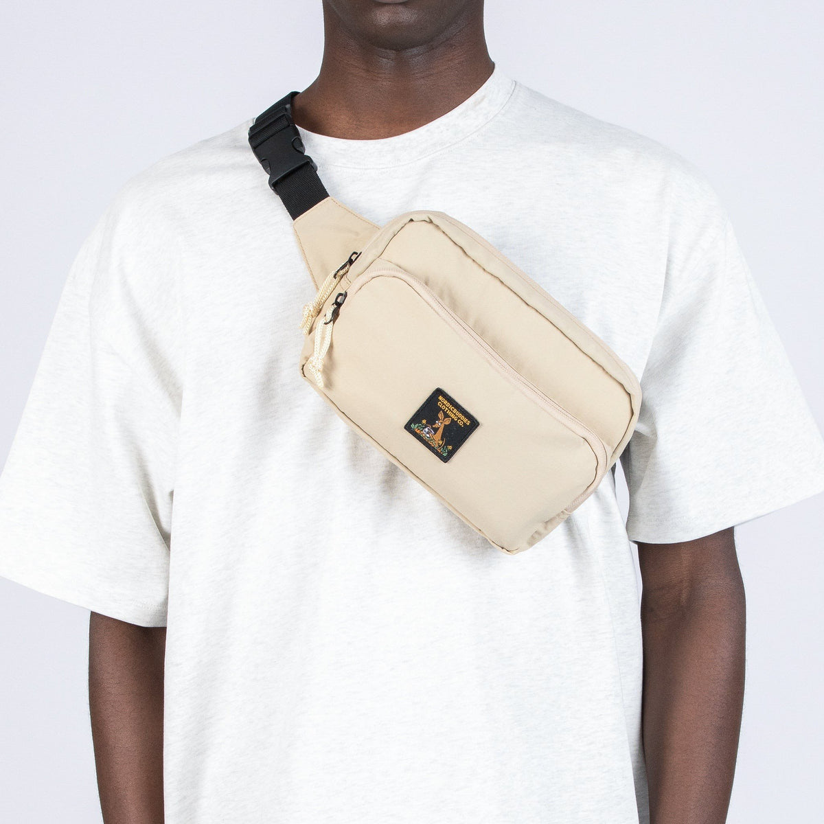1. Man wearing beige Sniff Retro Waist Bag by Moomin NordicBuddies across chest, casual white shirt