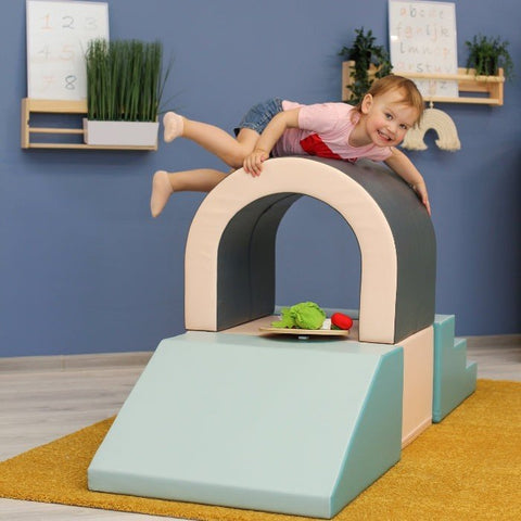 1. Child playing on IGLU pastel soft play tunnel set in indoor playroom with blue wall