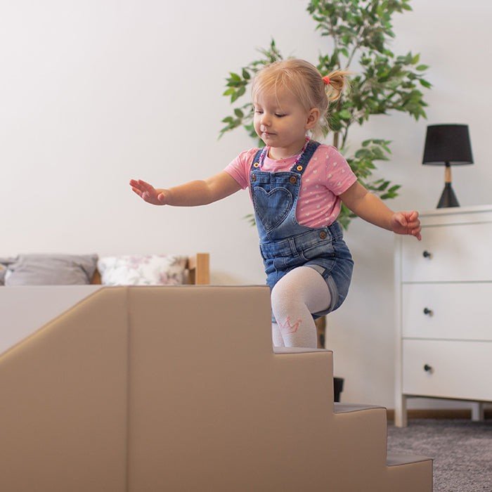 8. Toddler climbing beige and grey soft play steps in a cozy living room