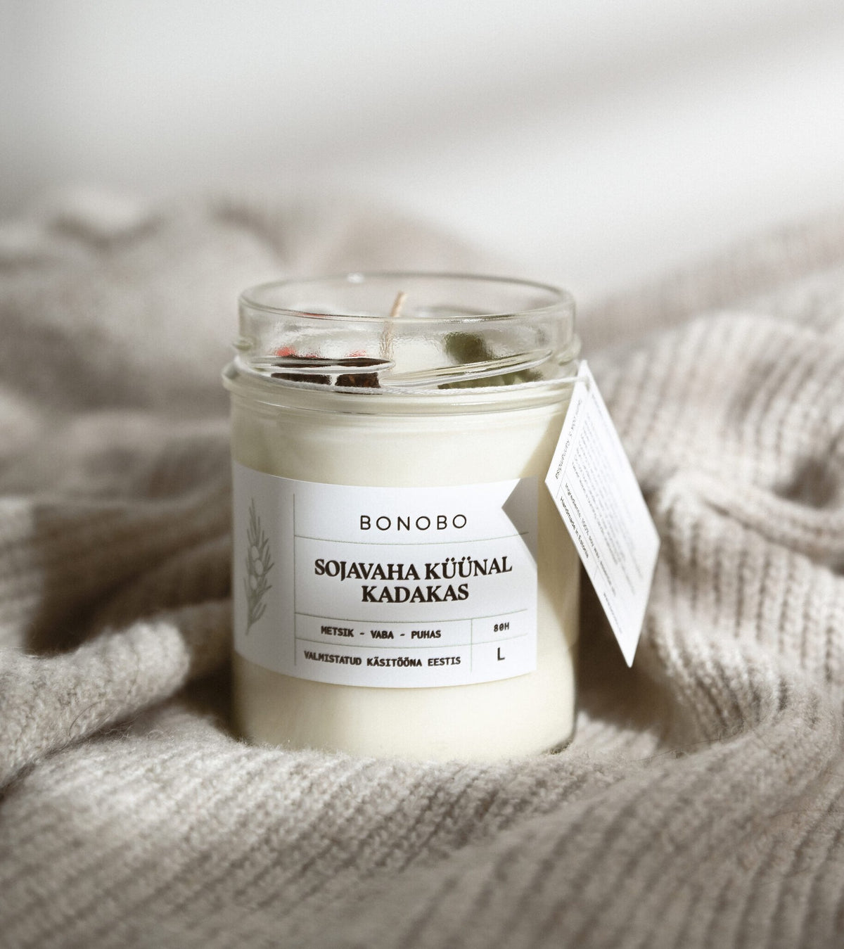 3. BONOBO juniper scented candle in a cozy setting, featuring soy wax and essential oils with label details