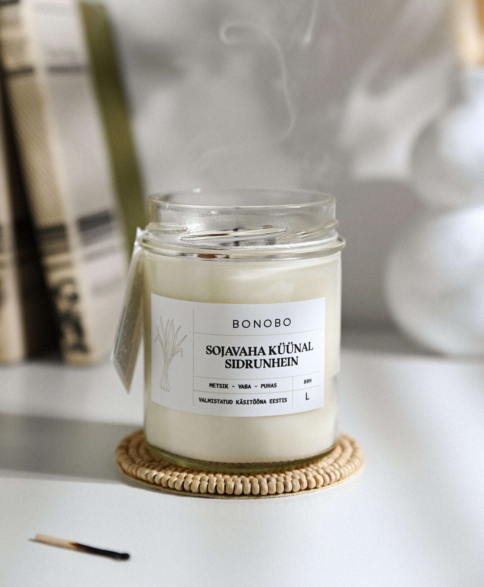3. Bonobo lemongrass scented candle in a glass jar with smoke, highlighting eco-friendly soy wax
