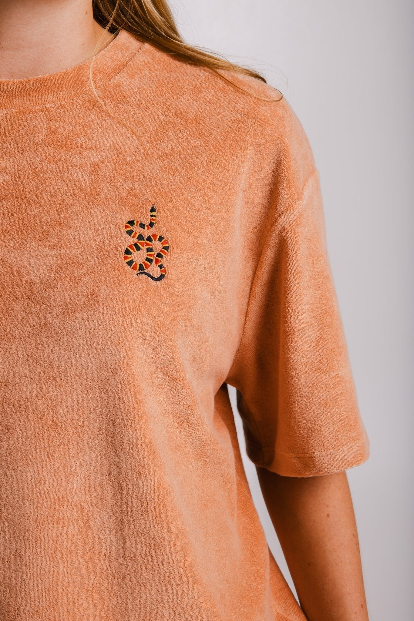 4. Close-up of Sossu Coral Snake Terry T-shirt in brown showing embroidered snake detail