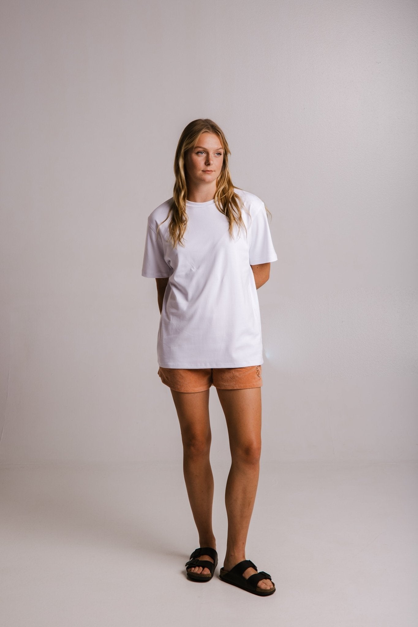 3. Full view of women's white heavy t-shirt by Sossu, styled with peach shorts and black sandals in studio
