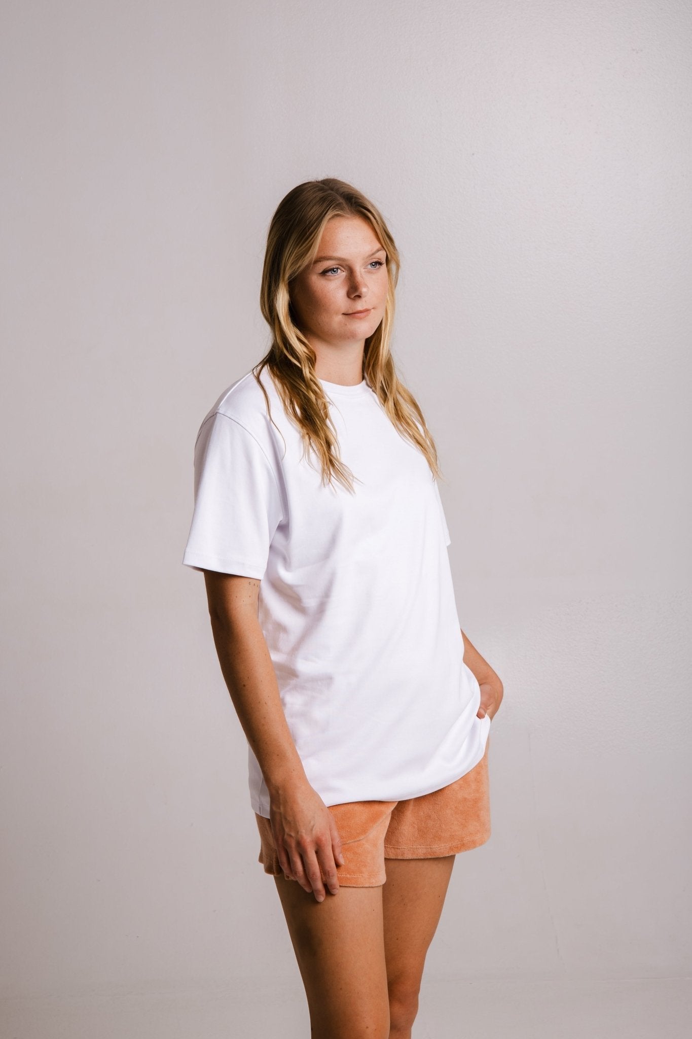 2. Side view of women's white heavy t-shirt by Sossu, paired with peach shorts in studio