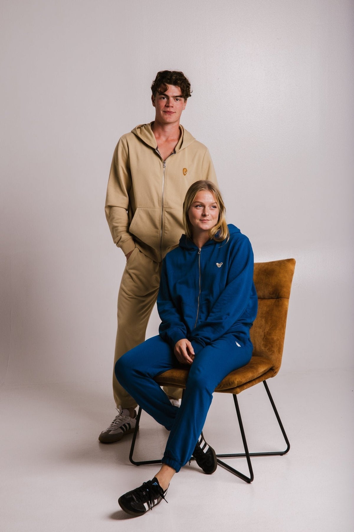 1. Unisex Lion Soft Fleece Full Zip Hoodie in light brown worn by male model, paired with blue hoodie on female model, studio setting