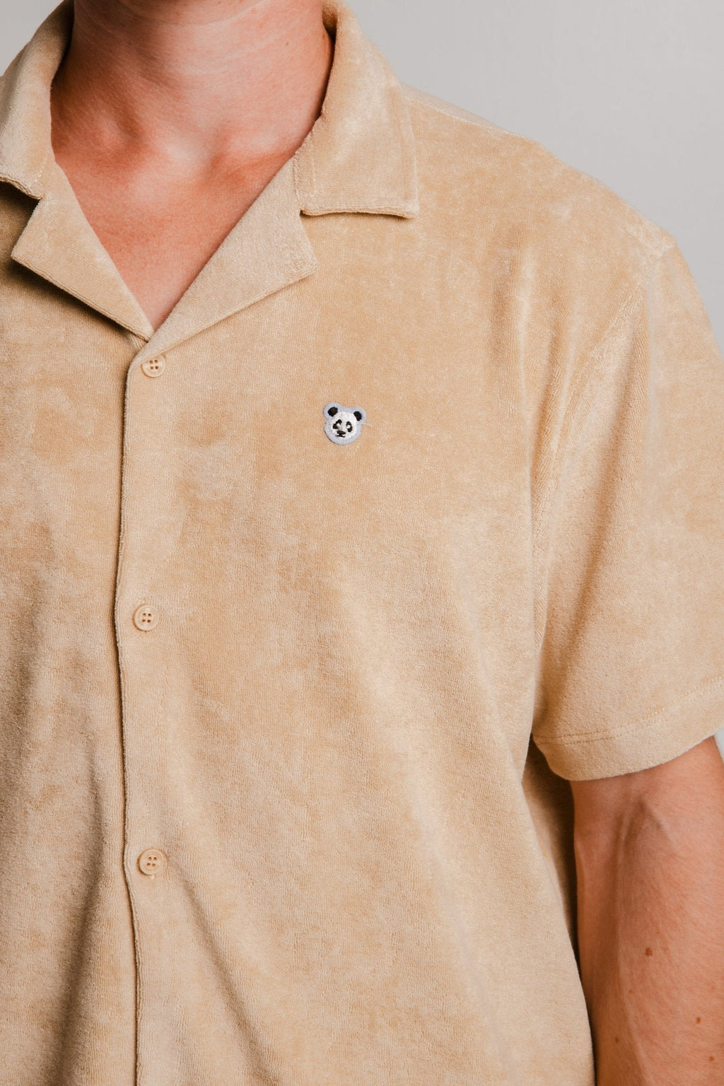 2. Close-up of Sossu Panda Terry Shirt in light brown showing embroidered panda detail, studio setting