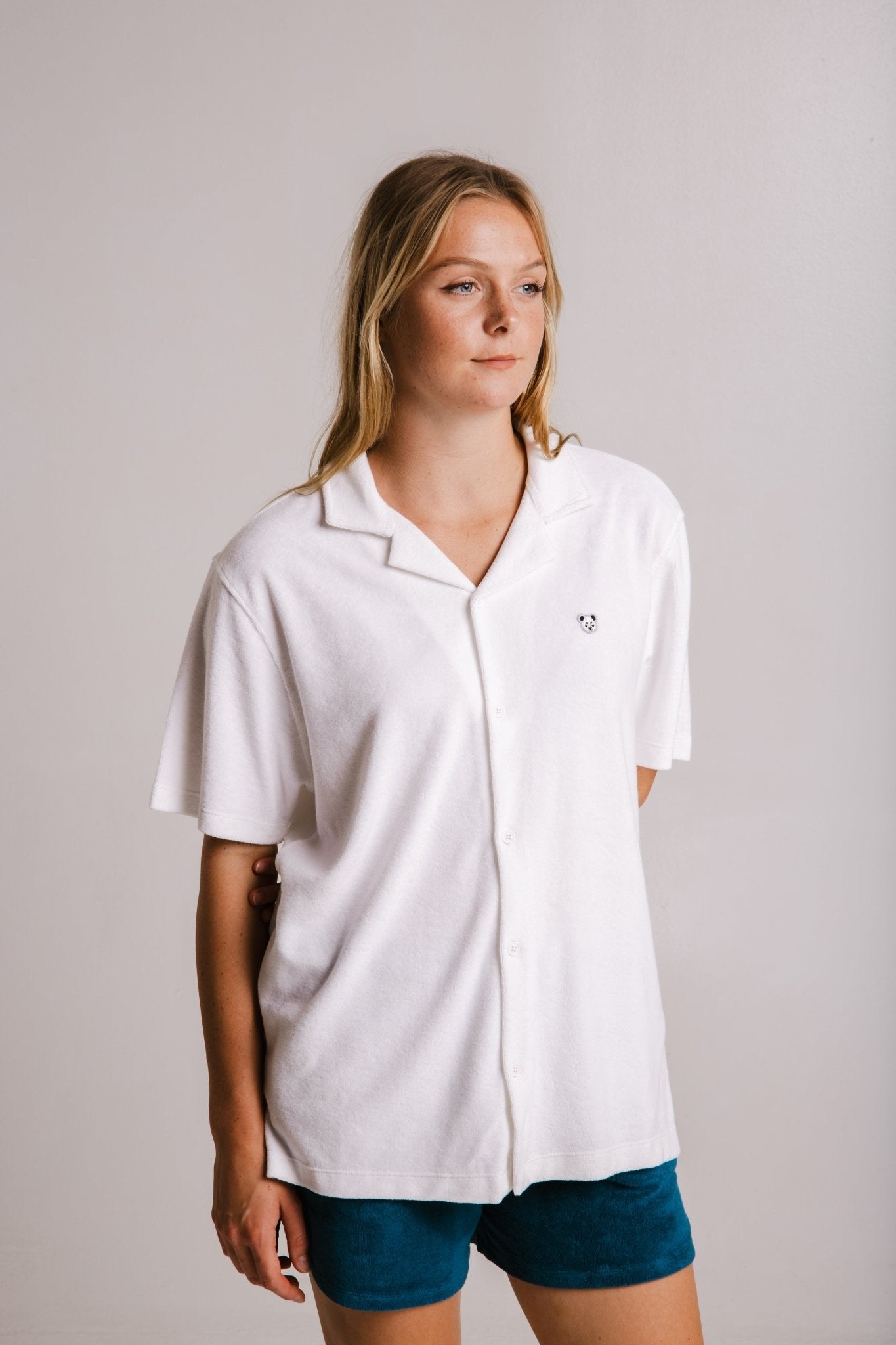 2. Women's white Panda Terry Shirt by Sossu, styled with blue shorts, showcasing a casual look in a studio