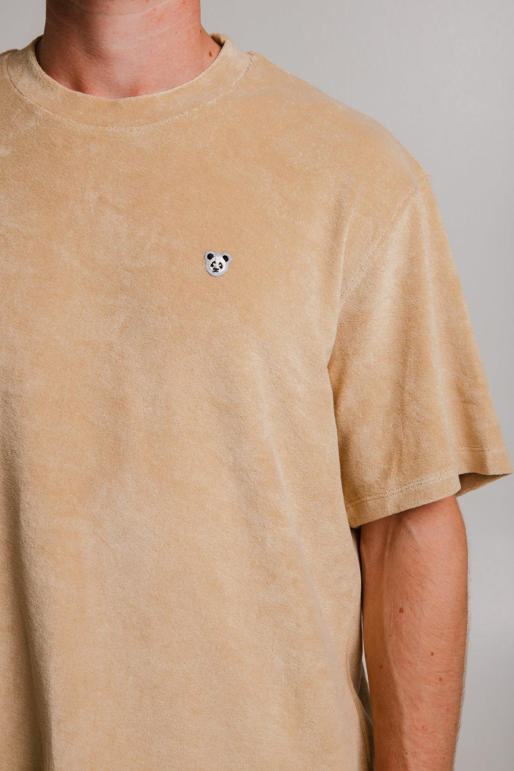 6. Close-up of panda logo on light brown Panda Terry T-shirt by Sossu, highlighting design detail