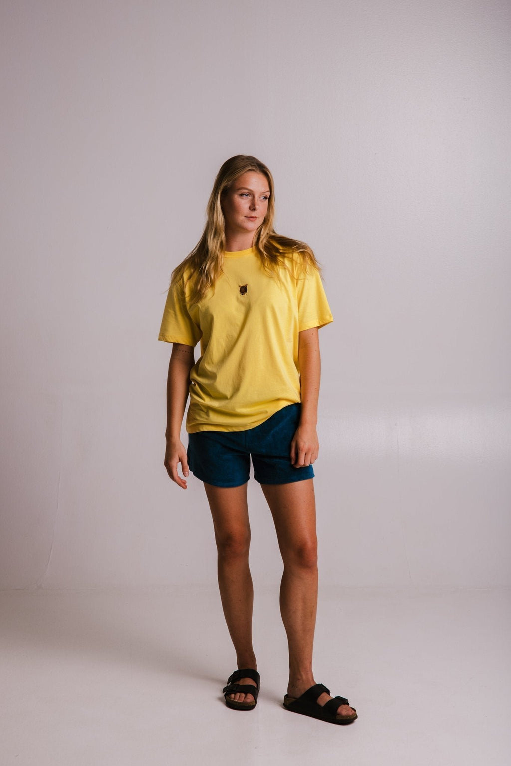 4. Full view of women's yellow Tiger T-shirt by Sossu, paired with blue shorts and sandals