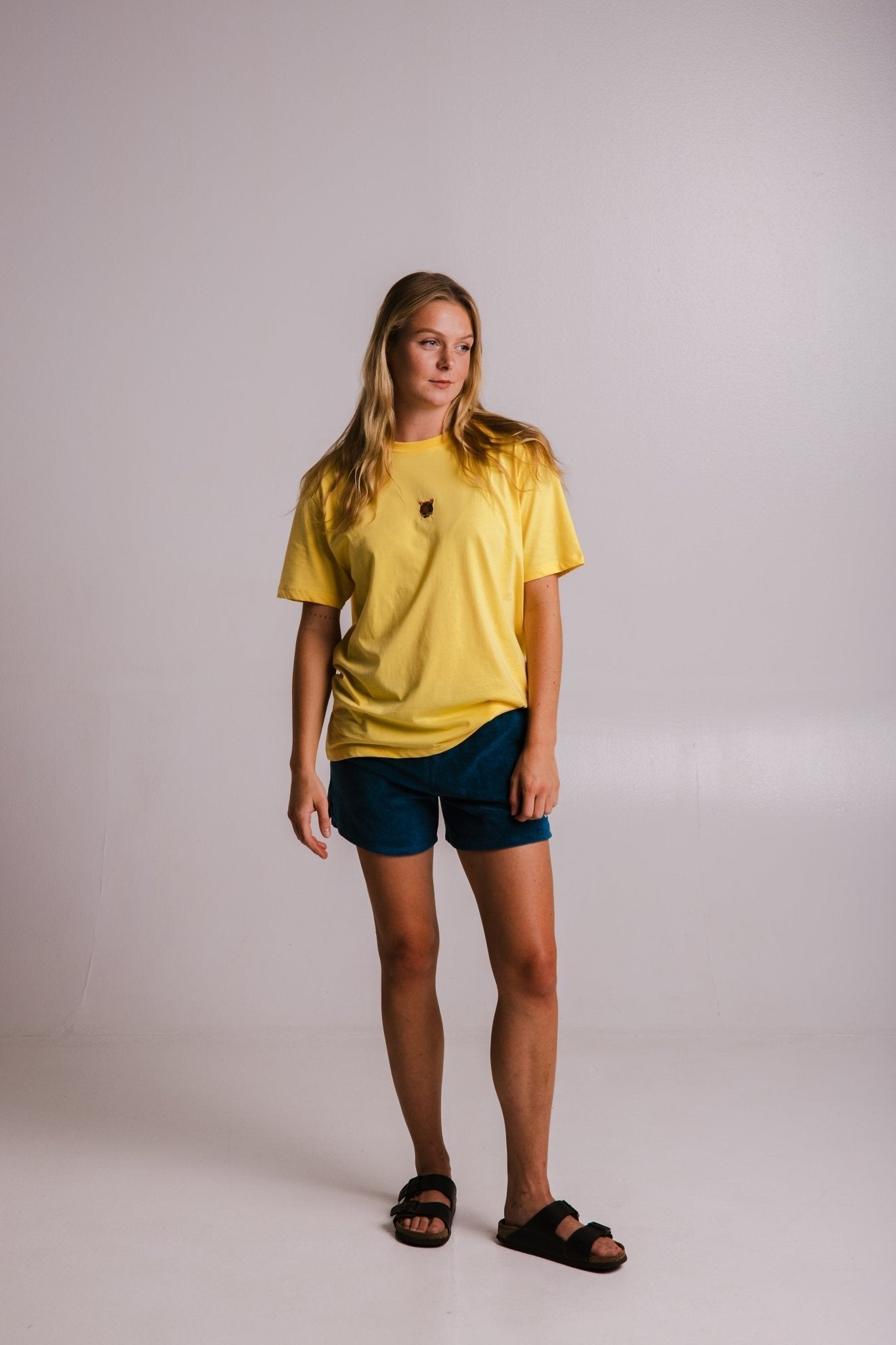 4. Full view of women's yellow Tiger T-shirt by Sossu, paired with blue shorts and sandals