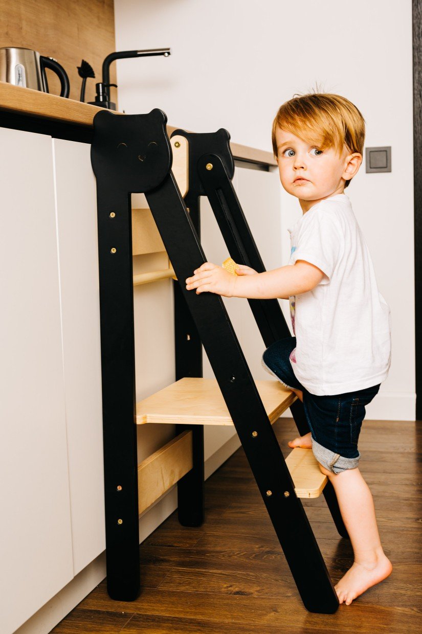 3. Child climbing black and natural wood step stool in kitchen