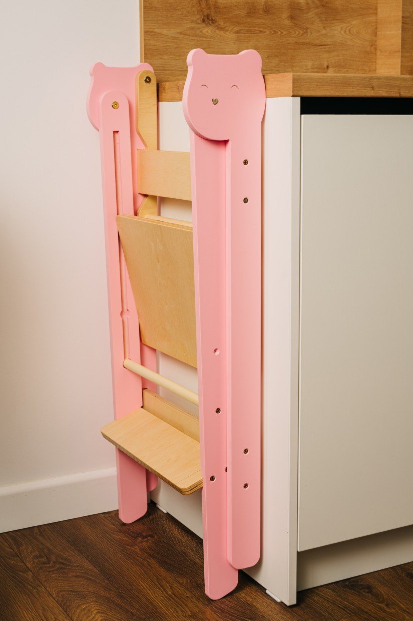 9. Folded pink step stool stored against kitchen cabinet