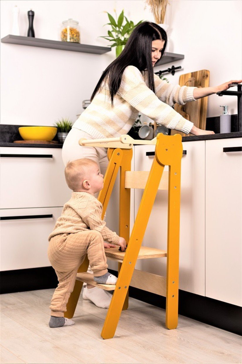 1. Woman and child using orange foldable step stool in modern kitchen setting