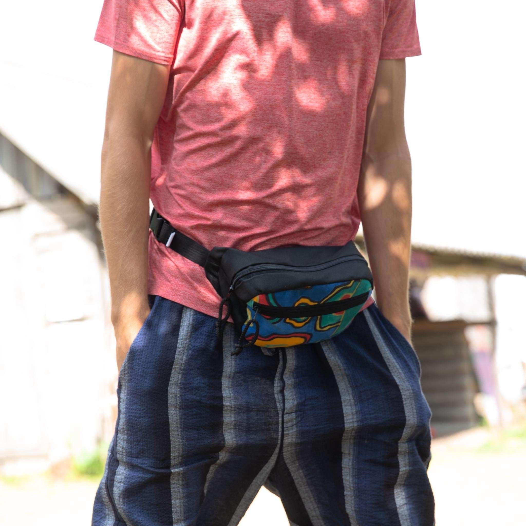 1. Man wearing Drinbags water-resistant waist bag with colorful print, styled with red shirt and blue pants outdoors