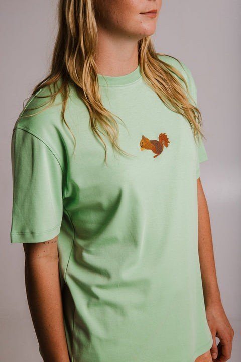 3. Close-up of Sossu Squirrel Heavy T-shirt in light green, highlighting embroidered design, worn by woman