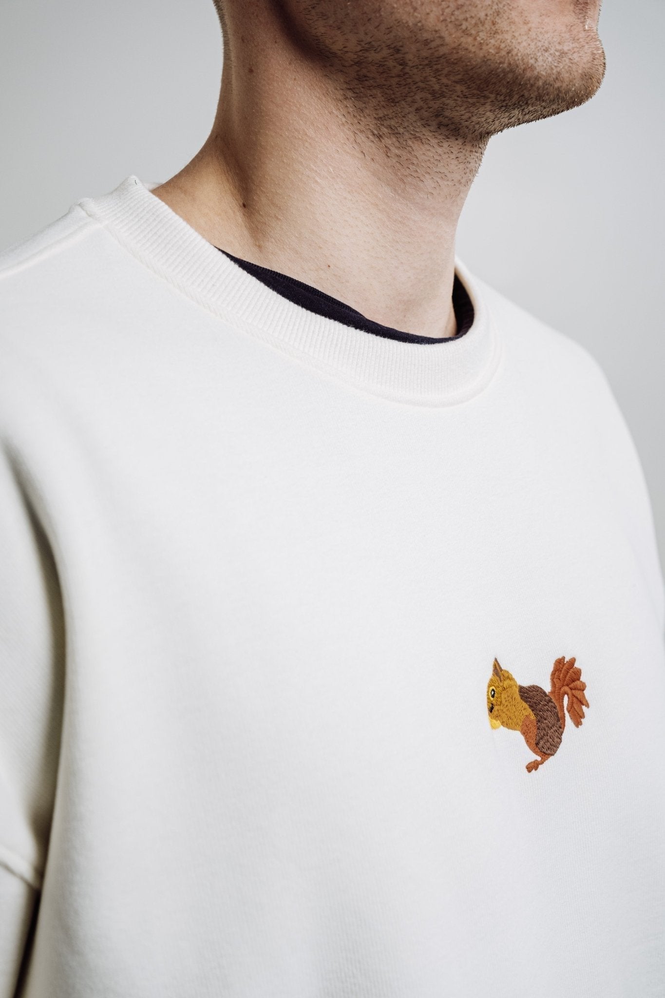4. Close-up of embroidered squirrel on cream Sossu Squirrel Sweatshirt, highlighting detail