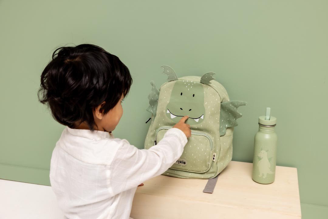 3. Child interacting with green dragon-themed backpack and matching stainless steel bottle on table