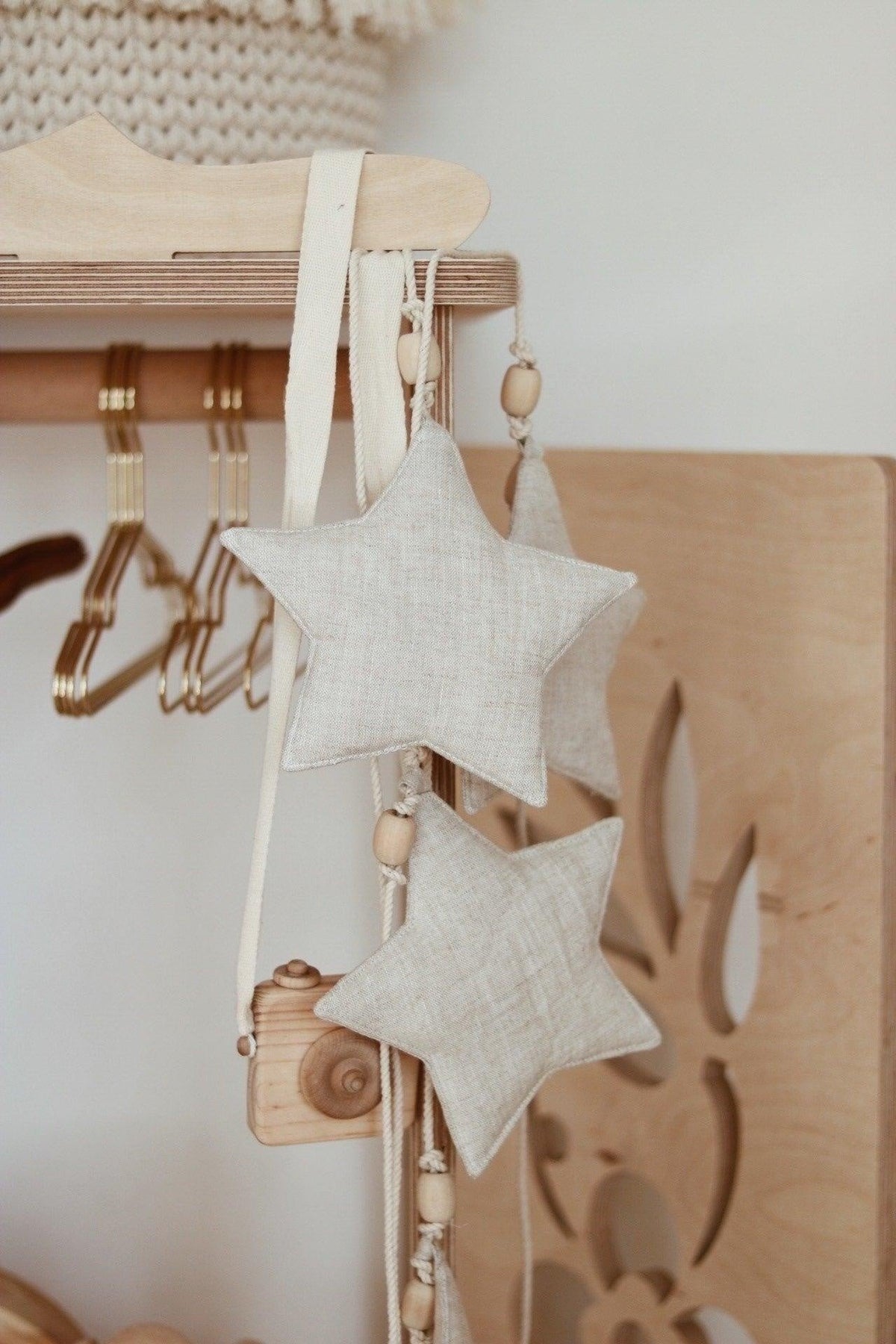 5. Linen star garland with wooden beads hanging on wooden rack, adding natural decor