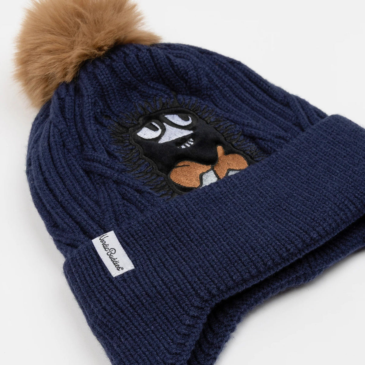 4. Flat lay of navy blue Moomin Stinky beanie with brown pom-pom and NordicBuddies logo