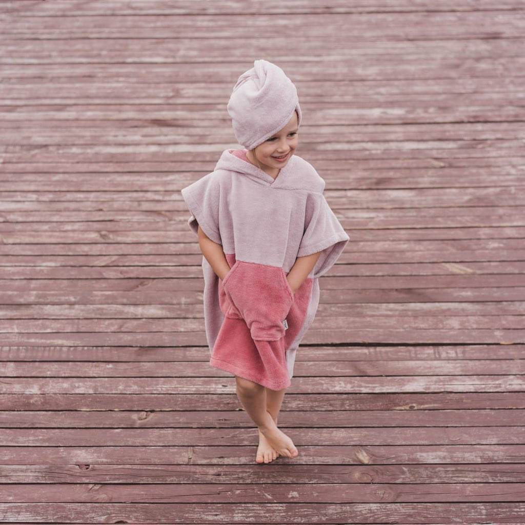 1. Child in pink Surfbunny bath poncho with bunny ears walking on wooden deck