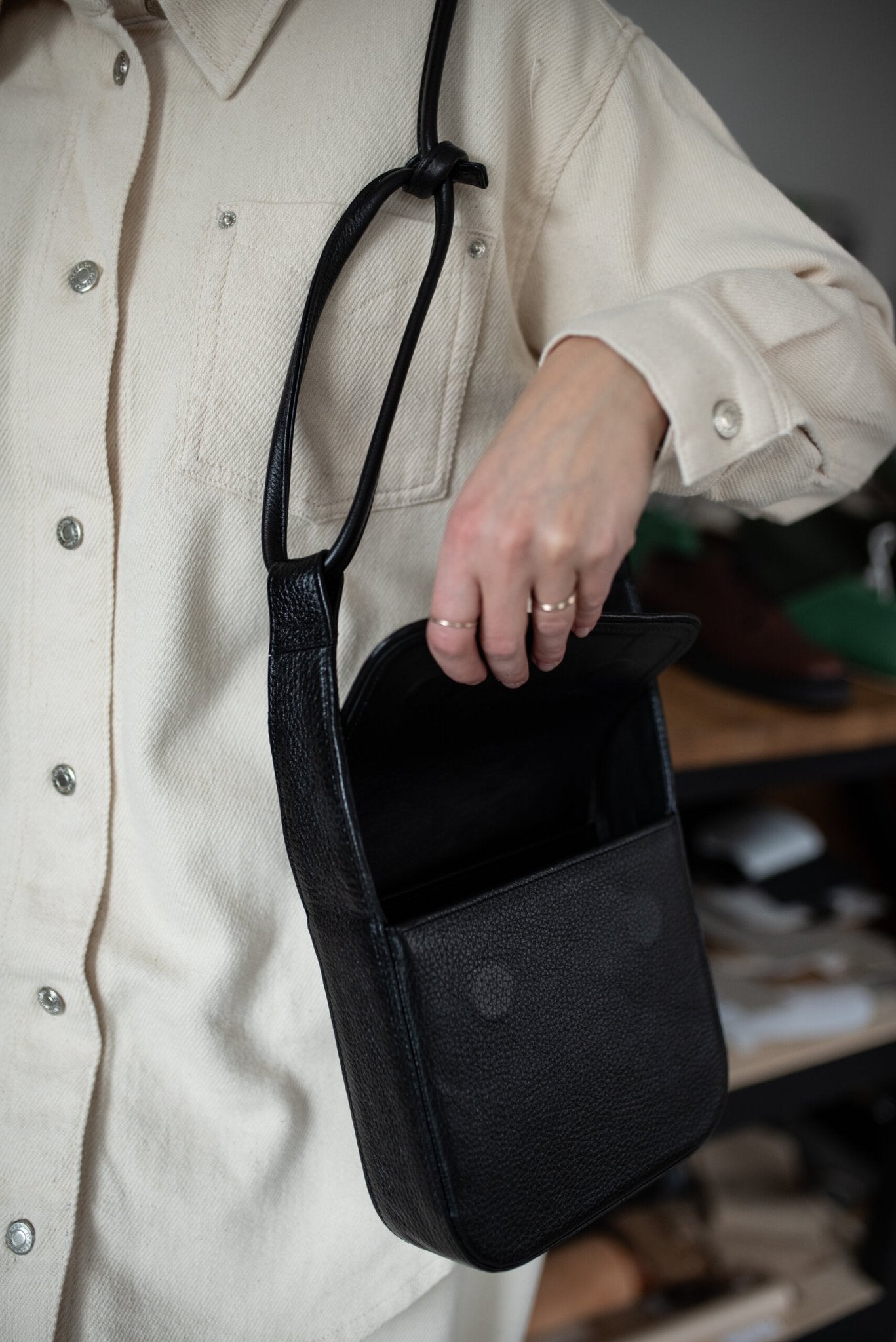 4. Black MUSA crossbody bag by Lava Flow, shown open with interior view, worn by model in cream outfit