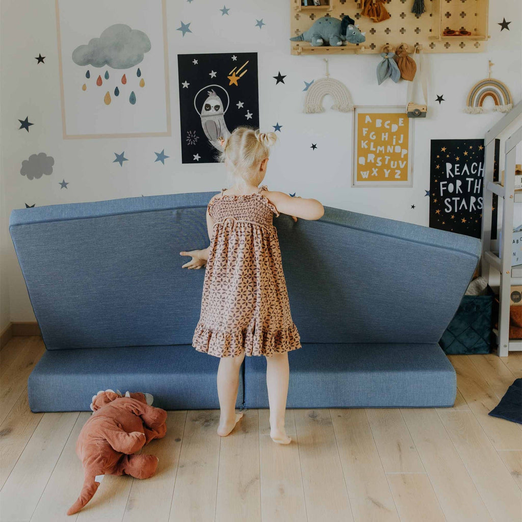14. Girl adjusting turquoise Monboxy play mattress in a star-themed children's room