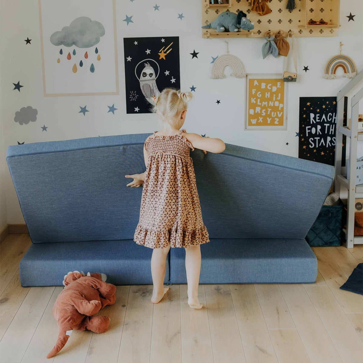 14. Girl adjusting turquoise Monboxy play mattress in a star-themed children's room