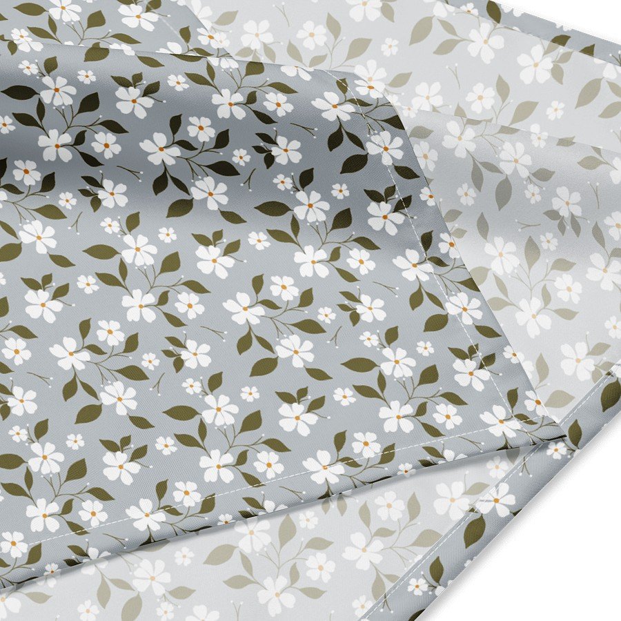 1. Close-up of Flowery Stories bandana with white blossom pattern on light grey background, showing fabric texture and floral design