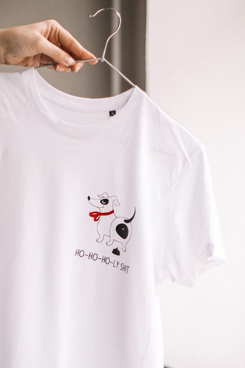 2. White T-shirt with dog graphic and 'Ho-ho-ho-ly sh*t' text held on hanger, showcasing design
