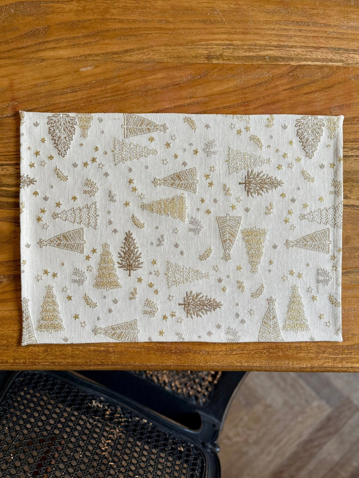 2. Studio shot of Hortensias Home Golden Forest table placemat with soft golden tree motif on a wooden table