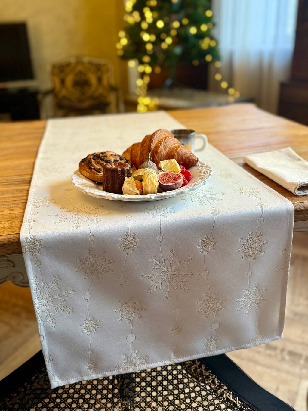 1. Golden Snowfall table runner by Hortensias Home on wooden table with festive pastries and coffee, Christmas tree in background