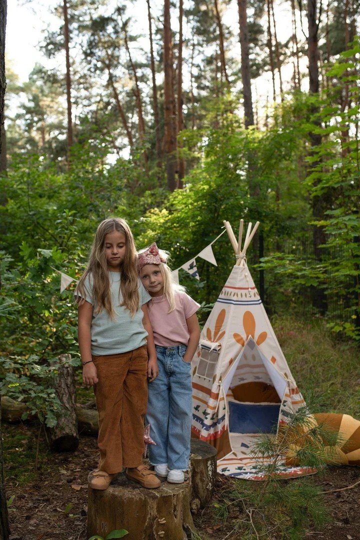 1. Two children standing in a forest next to Moi Mili teepee tent with geometric prints, creating an adventurous setting