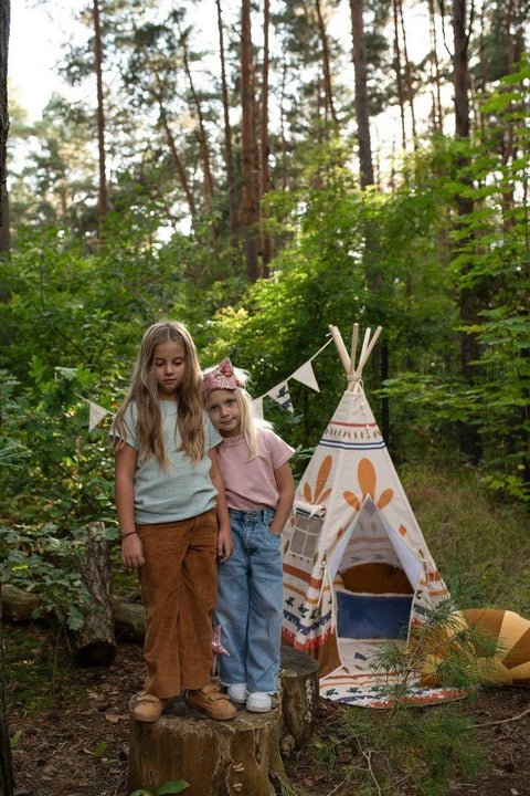 1. Two children standing in a forest next to Moi Mili teepee tent with geometric prints, creating an adventurous setting