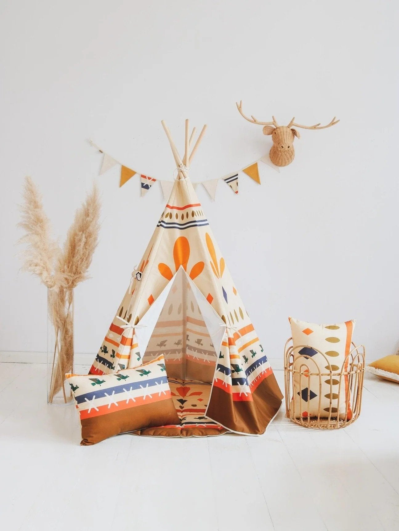 1. Moi Mili teepee tent with geometric prints in a bright room, decorated with a faux deer head and colorful pillows