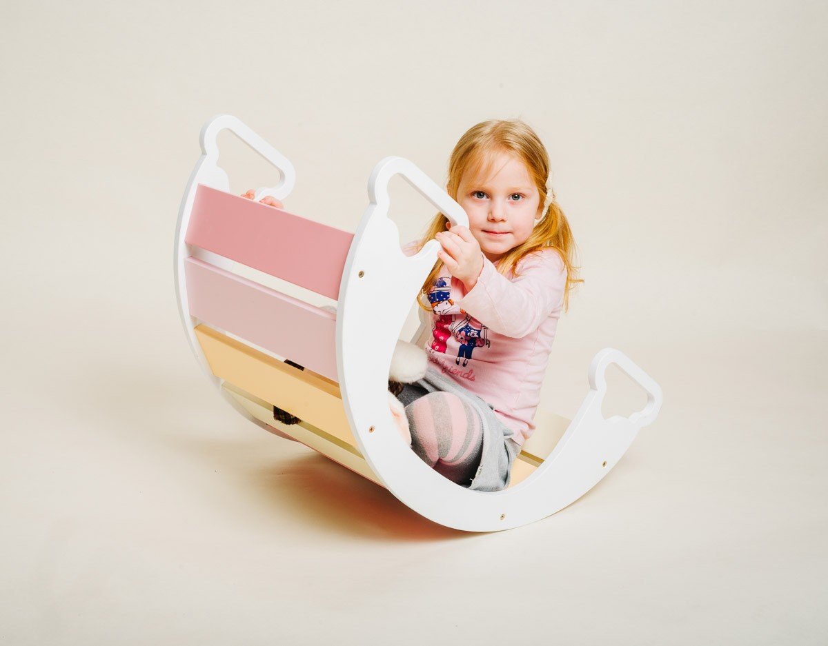 1. Child sitting inside colorful rainbow climber holding a toy