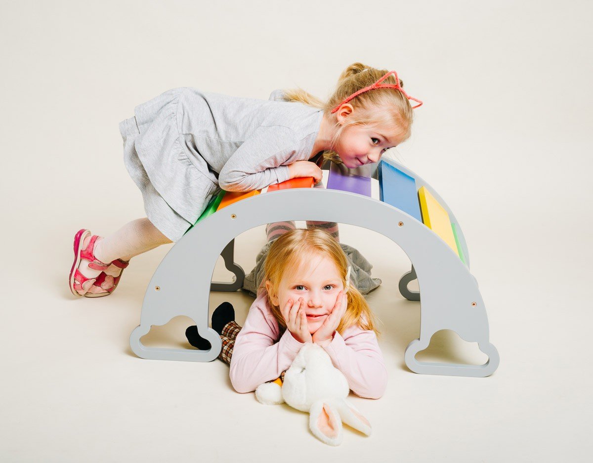 1. Two children playing on colorful rainbow climber, one lying on top, the other underneath