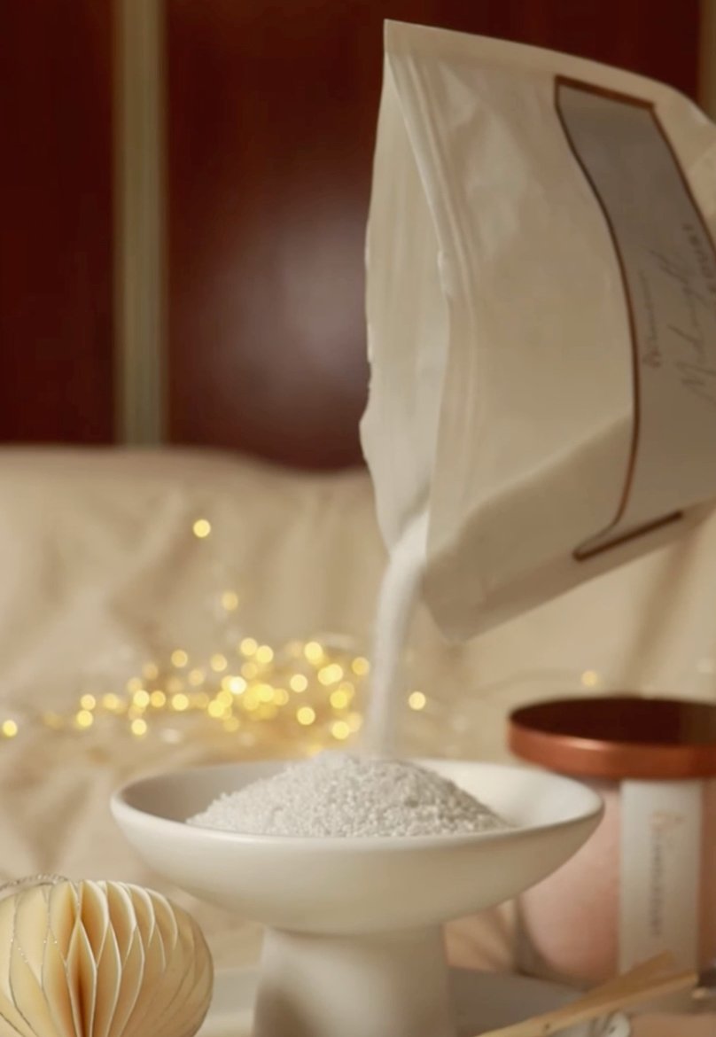 3. Candledust Nordic Lights powder being poured into a white bowl with festive lights