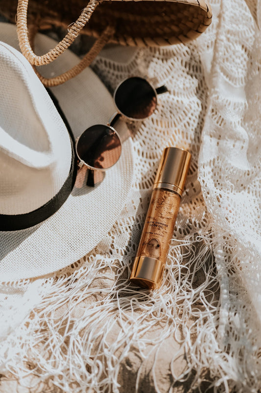 2. North Beauty Tinted Glow Oil bottle styled with summer accessories on a lace fabric