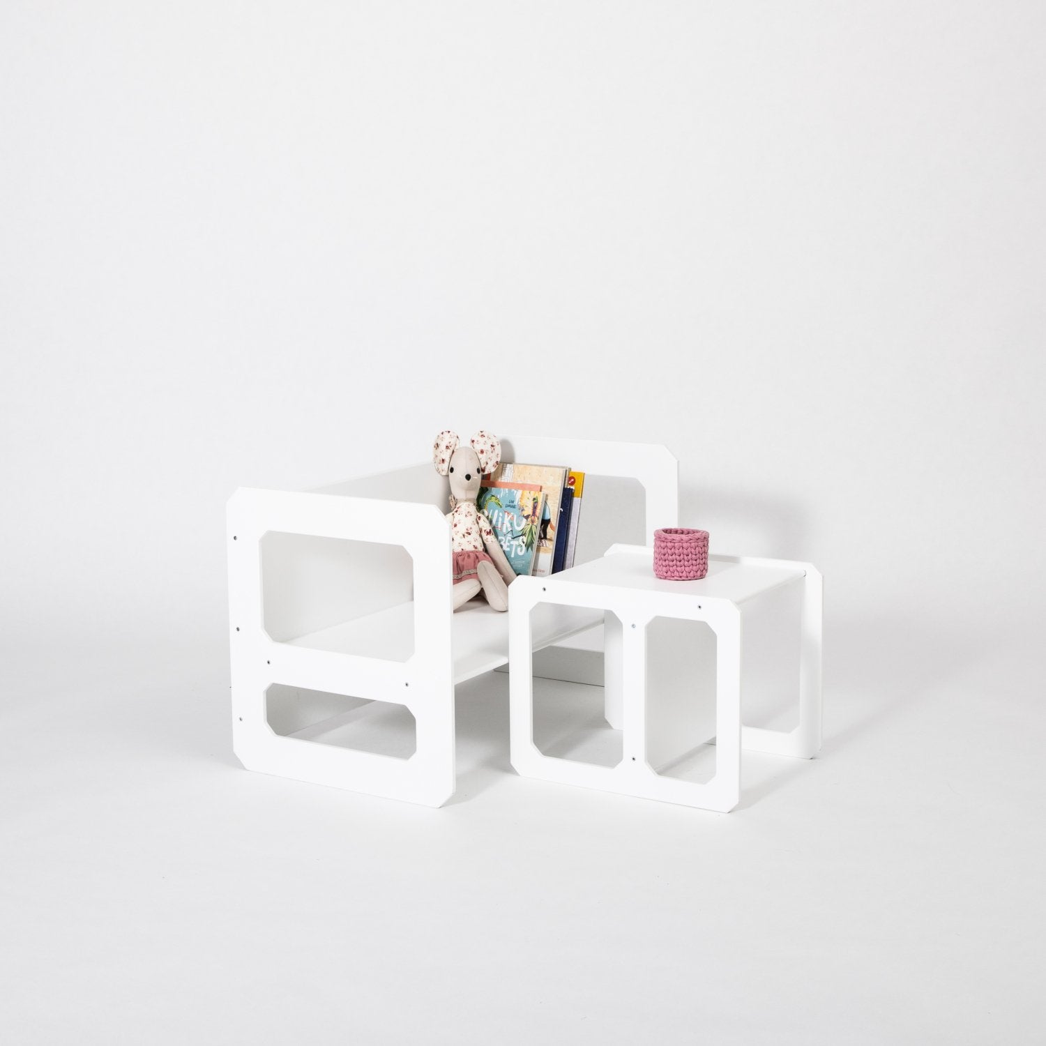 11. White Montessori weaning table and chair set with books and a pink cup on a white background