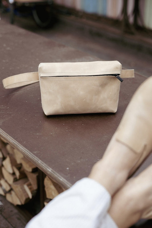 1. Beige TOKU Lisbon bag by Omaking on outdoor table, showcasing genuine leather and minimalist design