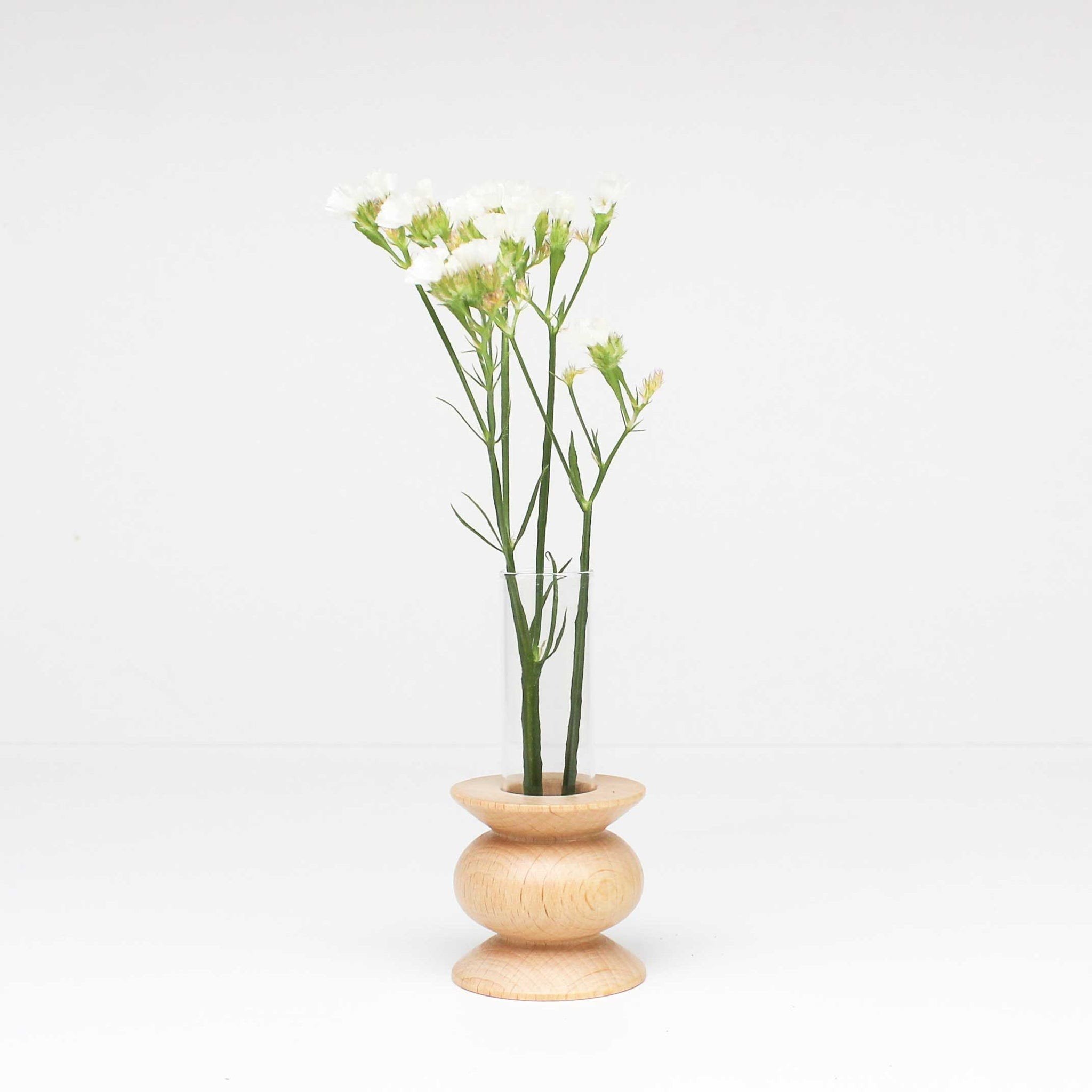 3. Studio shot of Totem Wooden Vase - Short Nº 5 by 5mm Paper with flowers, featuring beech wood base and removable glass tube