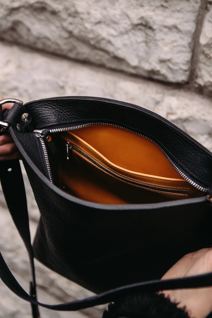 5. Interior view of black Stella Soomlais Escape Artist handbag showing orange lining and zippered pocket