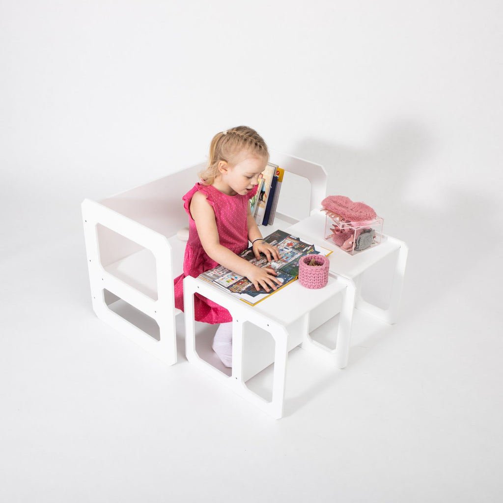 12. Girl in pink dress using white Montessori weaning table and chair set for reading on white background