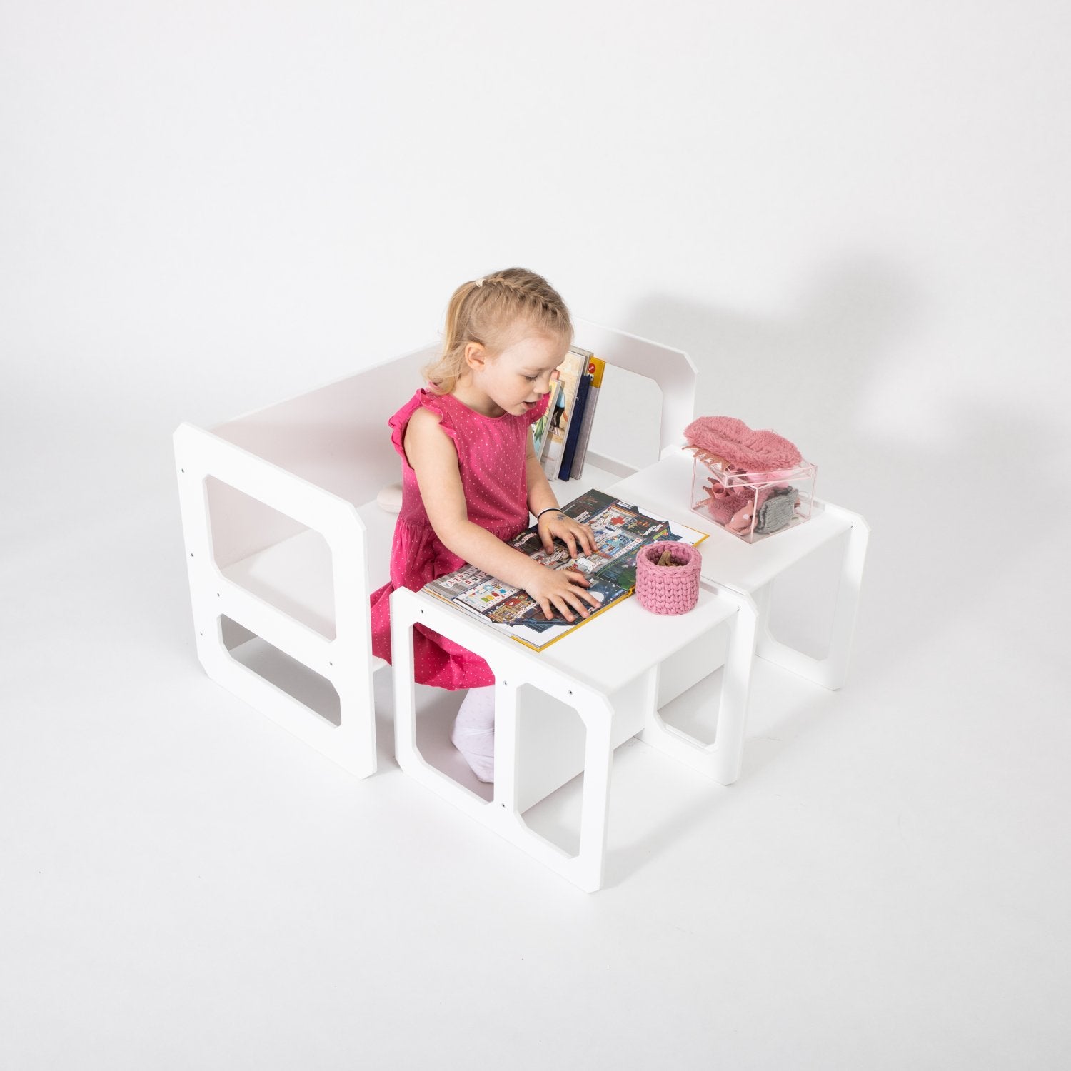 12. Girl in pink dress using white Montessori weaning table and chair set for reading on white background