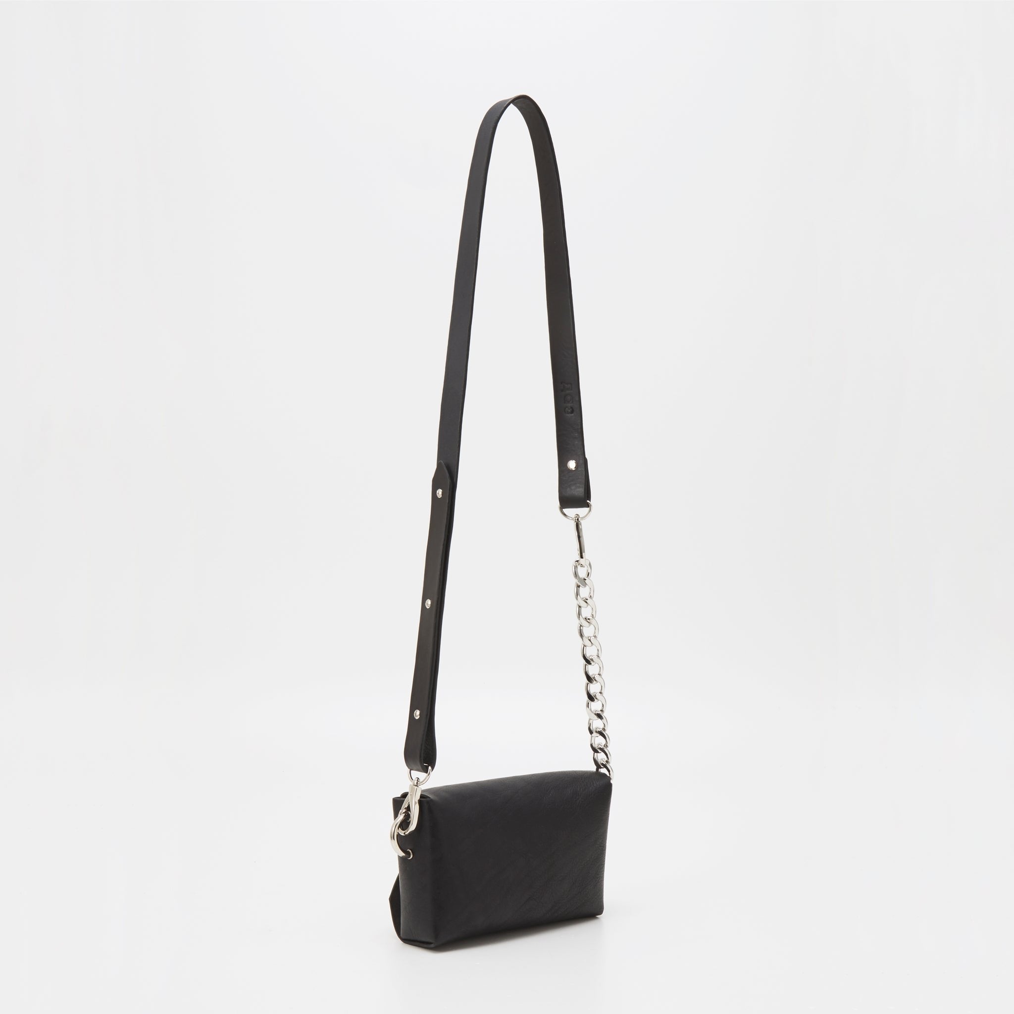 4. Studio image of handmade black leather envelope bag by Daz Studio with adjustable strap and chain detail