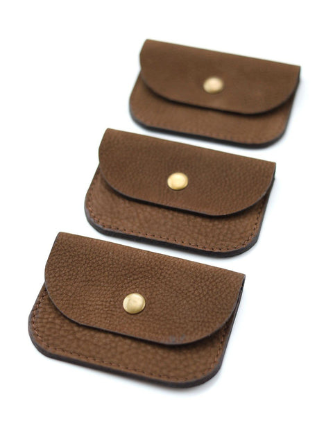 2. Three brown nubuck leather wallets with brass button closures arranged in a row on white background