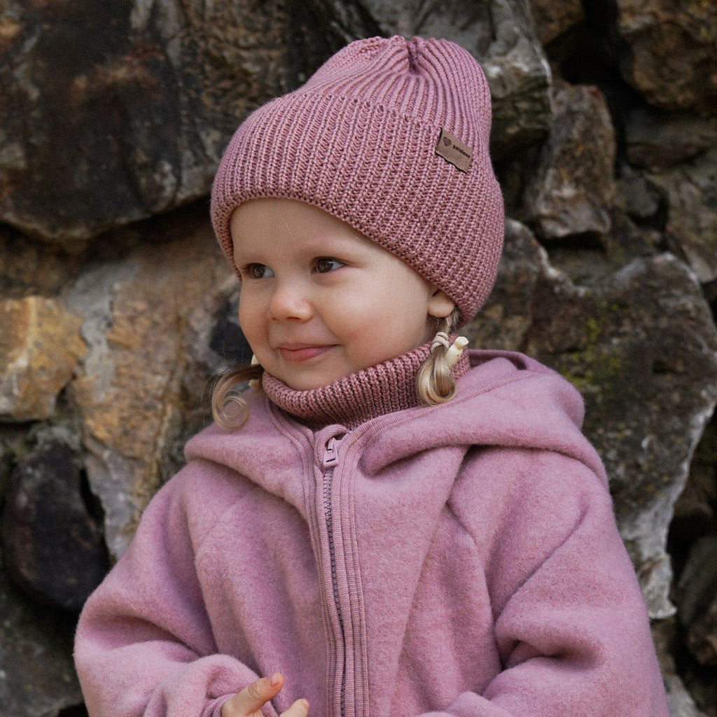 4. Child in blush merino wool hat and neck warmer against stone wall