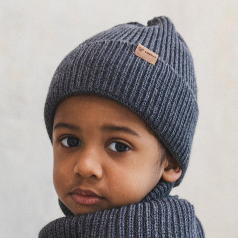 1. Child wearing graphite merino wool hat with Patulove logo, indoors, looking over shoulder